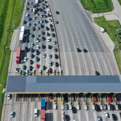 Widok z lotu ptaka na sznur samochodów stojących w kolejce do punktu poboru opłat na autostradzie.