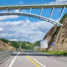 Autostrada A4 z wiaduktem, znakiem granicy Polski i białym samochodem.
